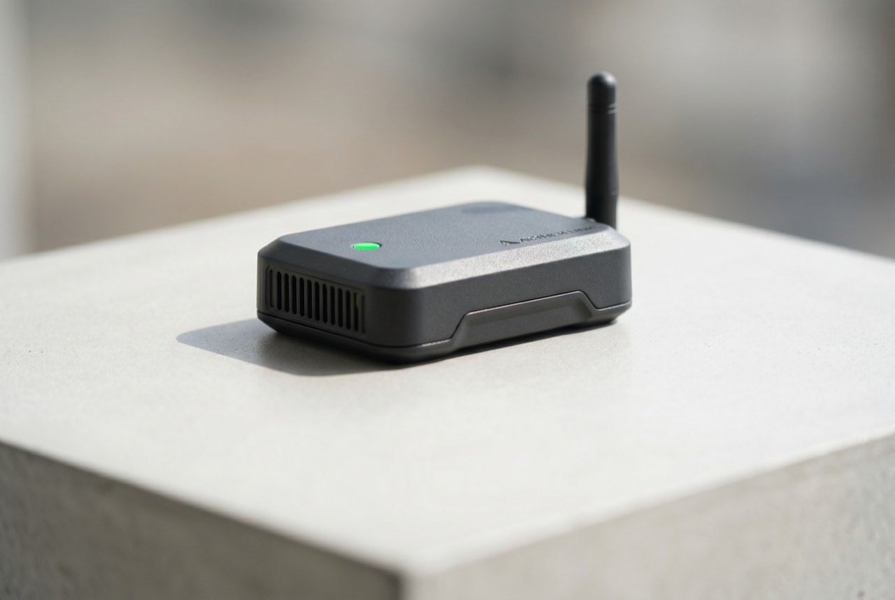 The Hop Bridge, a small matte-charcoal weatherproof device with a short antenna and a green status light